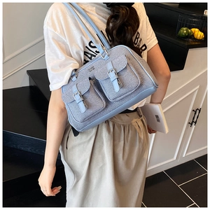 Close-up of light blue denim texture shoulder bag with double buckle pockets