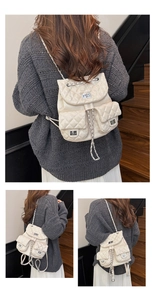 Details des cremefarbenen gesteppten PU-Rucksacks mit silbernem Drehverschluss und Kette