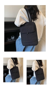 Detail of black quilted laptop bag featuring a large front flap pocket and shoulder strap