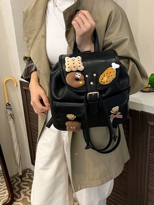 Fashionable black leather backpack for women with cute plush charms and bow detail