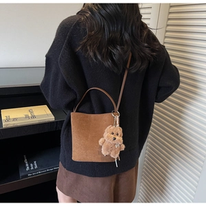 Détail d'un sac seau en daim marron avec charm ours en peluche et fine bandoulière