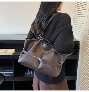 Détail du sac cabas en cuir marron avec boucle latérale et accessoires en métal argenté