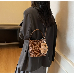 Détail du sac seau à imprimé léopard avec breloque peluche et bandoulière en cuir
