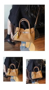 Detalle del bolso de ante marrón con cierre metálico y colgantes decorativos de madera