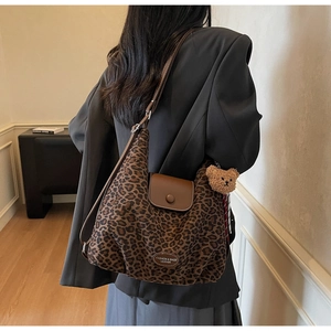 Detail of leopard print tote bag featuring brown leather flap and cute bear pendant charm