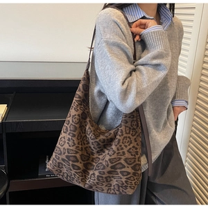 Detail view of a vintage leopard print suede tote bag worn on shoulder by a model