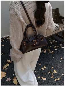 Close-up of vintage dark brown leather boston bag with gold buckles in autumn setting