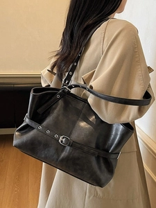 Grand sac cabas noir avec boucles argentées porté par un mannequin en trench-coat chic