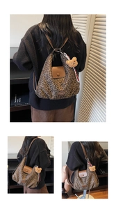 Detail of leopard print tote bag with brown leather strap and a plush bear charm