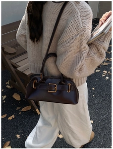 Detail of dark brown leather tote bag with gold hardware and stylish long shoulder strap