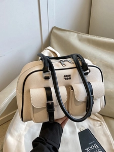 Vintage-style cream woven pillow bag with black leather trim and twin metal buckle pockets