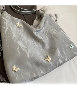 Silver-grey pleated tote bag featuring metallic butterfly studs and soft plush charm