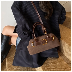 Detail of dark brown suede shoulder bag with gold buckles and vintage retro style
