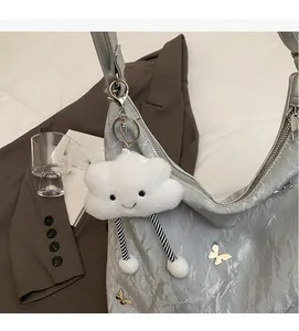 Detail of creative plush cloud pendant with striped legs on a silver textured bag