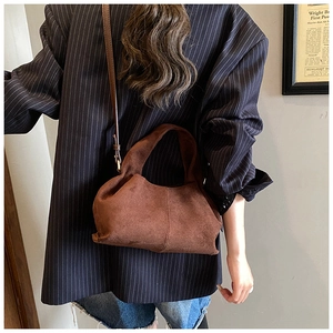 Sac nuage en daim marron porté en bandoulière sur un mannequin au style vintage