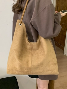 Large camel suede hobo tote bag shown on shoulder with minimalist stitching and metal rings