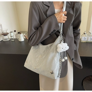 Detail of silver metallic wrinkled tote bag with butterfly charms and cloud pendant