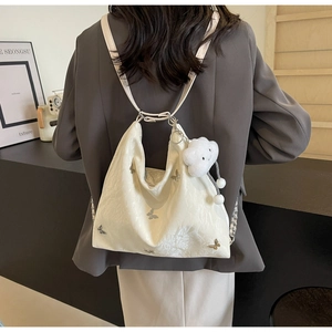 Detail of white textured hobo bag featuring silver butterflies and a plush cloud charm