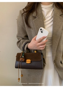 Detail of a retro crossbody bag in deep brown leather with a vintage metal buckle lock
