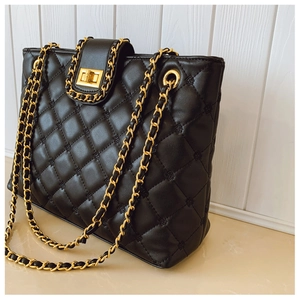 Detail of black quilted leather shoulder bag featuring gold chain and turn-lock closure