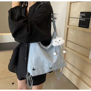 Detail of light blue embroidered tote bag featuring butterfly patches and cloud charm