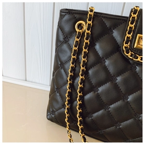 Detail of black quilted shoulder bag with gold chain strap and diamond embroidery