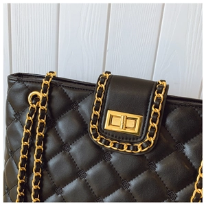 Detailed shot of black quilted bag featuring gold twist lock and chain strap