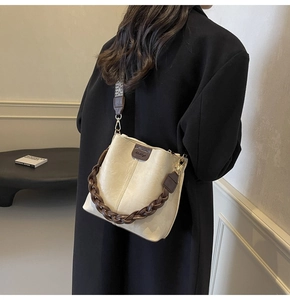 Chic cream bucket bag featuring a vintage woven strap and premium hardware detail