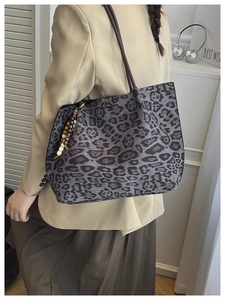 Dettaglio della borsa tote leopardata con tracolla marrone e ciondolo a nappa in legno