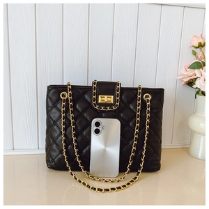 Detail of black quilted shoulder bag with gold chain strap and turn-lock closure