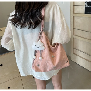 Detail of light pink pleated tote bag with silver butterflies and plush cloud charm