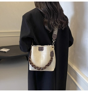 Detail of cream leather bucket bag showing woven handle and boho print wide strap