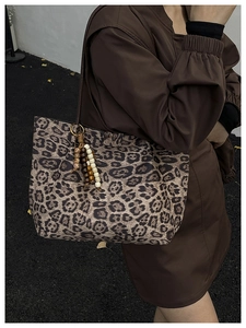 Dettaglio della borsa tote leopardata con ciondoli in legno e materiale testurizzato