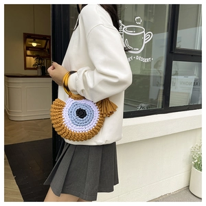 Detail of hand-woven crochet eye bag with tortoiseshell handle and tassel accent