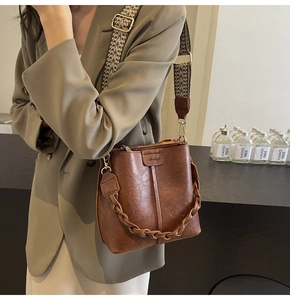 Detail of vintage brown bucket bag with wide jacquard strap and oil wax leather texture