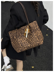 Detail of leopard print tote bag with wooden bead tassel and brown leather shoulder strap