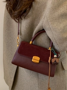 Retro burgundy leather crossbody bag with suede flap and gold buckle on a stylish model