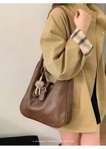 Détail d'un sac hobo rétro marron foncé avec un charme en peluche et boucle de fermeture