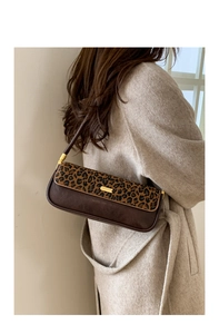 Retro leopard print baguette bag shown from a side perspective on a beige wool coat