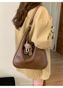 Détail du sac cabas rétro marron foncé avec pompon en peluche sur la bandoulière
