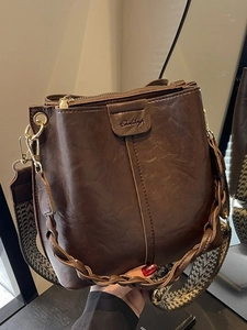 Brown bucket bag with textured leather, woven handle and geometric fabric strap