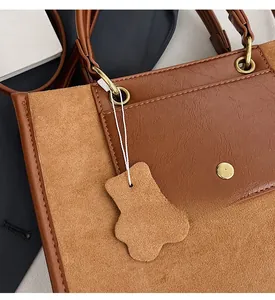 Detail of caramel brown tote bag featuring suede texture and cute bear pendant charm