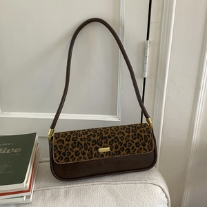 Macro detail of leopard print flap and golden buckle on brown leather baguette bag
