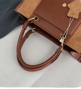 Close-up of contrast brown tote bag handle with vintage gold hardware and stitching