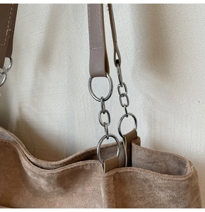 Close-up of suede tote bag with silver metal ring and chain strap detail in brown