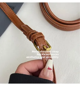 Detail of adjustable brown leather strap featuring a polished gold hardware buckle