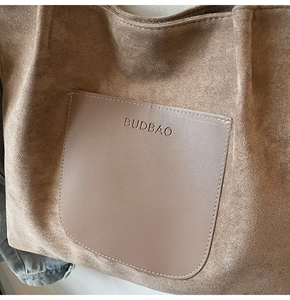 Detailed view of the suede leather tote bag featuring a contrast logo embossed pocket