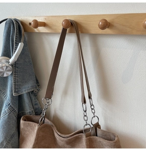 Detail of the brown suede tote bag featuring a leather and metal chain shoulder strap