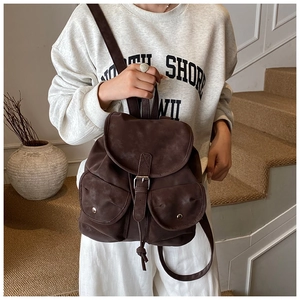 Close-up of retro dark brown backpack with drawstring flap and metal buckle details
