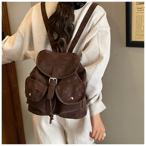 Detailed back view of a dark brown vintage backpack worn by a model in an indoor setting